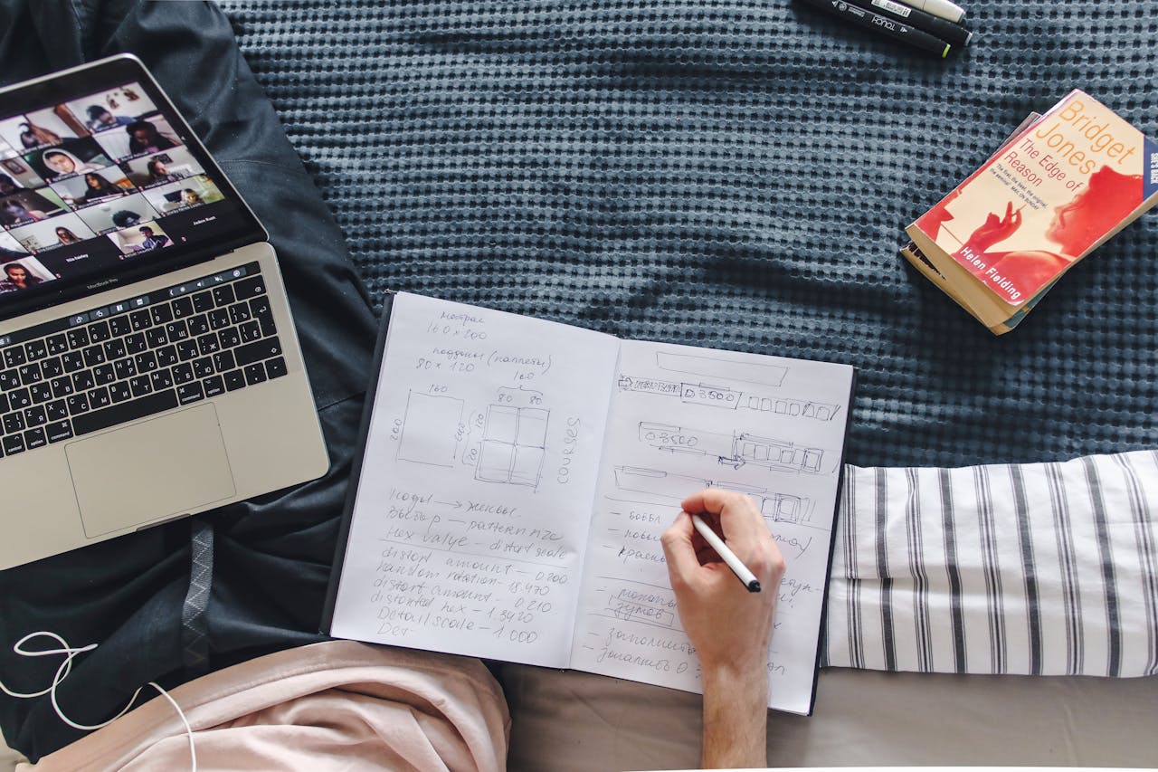 A cozy study setup with a laptop, notebook, and book, depicting remote learning in a relaxed environment.